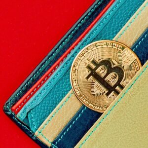 Bitcoin in physical wallet on red background