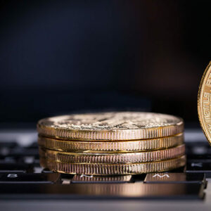 Stack of gold bitcoins on top of laptop