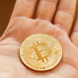 Gold bitcoin on palm of hand
