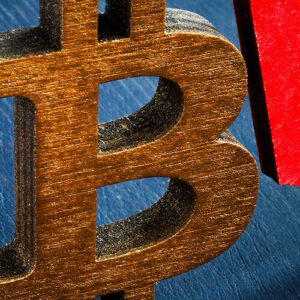 Bitcoin icon in brown wood beside red arrow